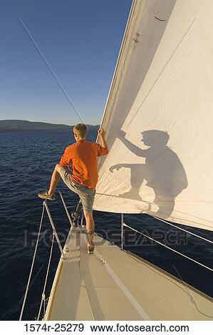 Stock Photo - Rear view of a man standing on a sailboat. Fotosearch