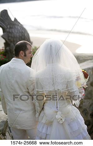 Rear view of a newlywed couple walking together View Large Photo Image Stock Photo - Rear view of a newlywed couple walking together. Fotosearch