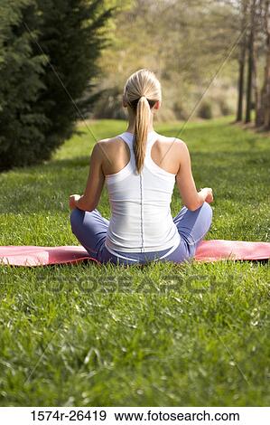 Rear view of a young woman meditating View Large Photo Image Stock Photo - Rear view of a young woman meditating. Fotosearch