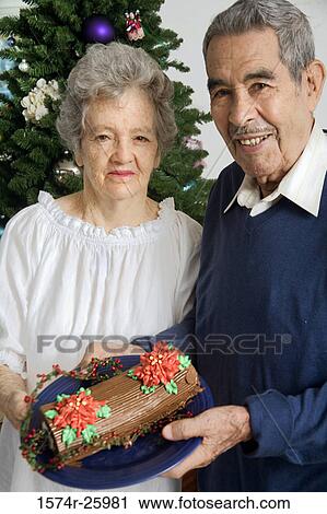 Senior couple holding a Yule log shaped cake and smiling View Large Photo Image Stock Image - Senior couple holding a Yule log shaped cake and smiling. Fotosearch