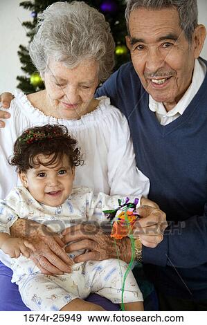 Stock Photo - Senior couple holding their great-grandchild and smiling. Fotosearch