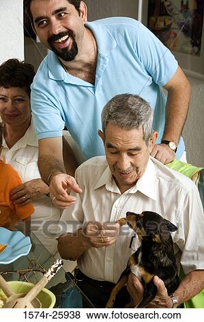 Senior man feeding a dog with a mature man standing behind View Large Photo Image Stock Photo - Senior man feeding a dog with a mature man standing behind. Fotosearch