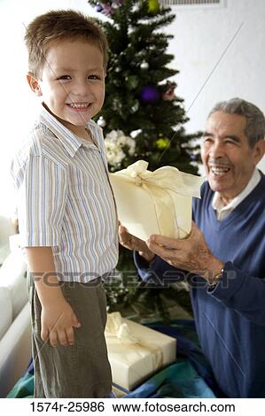 Senior man giving a gift to his great-grandson and smiling View Large Photo Image Stock Photograph - Senior man giving a gift to his great-grandson and smiling. Fotosearch