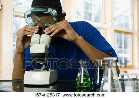 Student looking through a microscope in a science lab View Large Photo Image Stock Photo - Student looking through a microscope in a science lab. Fotosearch
