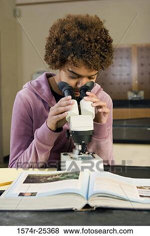 Stock Photo - Student looking through a microscope in a science lab. Fotosearch