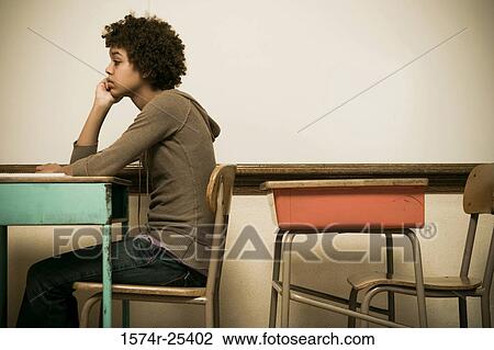 Stock Image - Student sitting at a desk in a classroom. Fotosearch