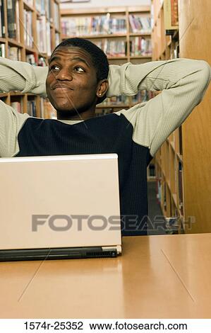 Student sitting in front of a laptop in a library View Large Photo Image Stock Image - Student sitting in front of a laptop in a library. Fotosearch