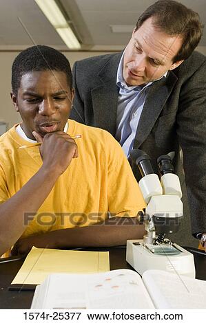 Student thinking with his teacher standing behind him View Large Photo Image Stock Photo - Student thinking with his teacher standing behind him. Fotosearch