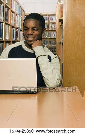 Student using a laptop in a library View Large Photo Image Stock Image - Student using a laptop in a library. Fotosearch