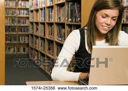 Student using a laptop in a library View Large Photo Image Stock Photograph - Student using a laptop in a library. Fotosearch