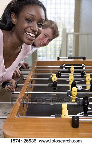 Teenage boy and a young woman playing foosball View Large Photo Image Stock Photograph - Teenage boy and a young woman playing foosball. Fotosearch