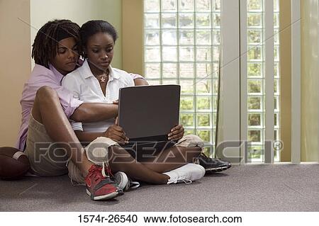 Teenage boy sitting behind a young woman using a laptop View Large Photo Image Stock Image - Teenage boy sitting behind a young woman using a laptop. Fotosearch