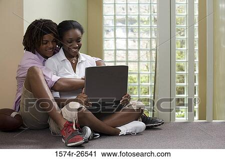 Teenage boy sitting behind a young woman using a laptop View Large Photo Image Stock Image - Teenage boy sitting behind a young woman using a laptop. Fotosearch