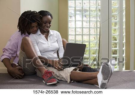 Teenage boy sitting behind a young woman using a laptop View Large Photo Image Stock Photo - Teenage boy sitting behind a young woman using a laptop. Fotosearch