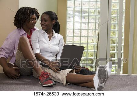 Stock Photo - Teenage boy sitting behind a young woman using a laptop. Fotosearch