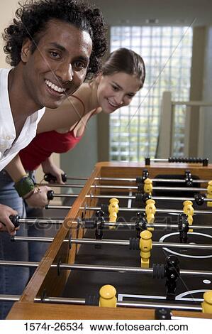 Teenage girl and a young man playing foosball View Large Photo Image Picture - Teenage girl and a young man playing foosball. Fotosearch