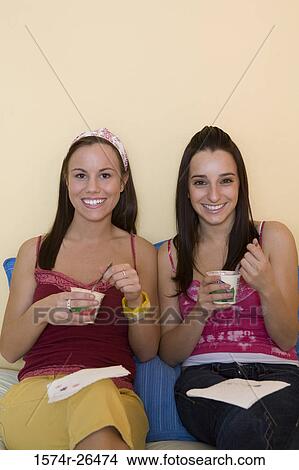Picture - Teenage girl and a young woman sitting and eating. Fotosearch