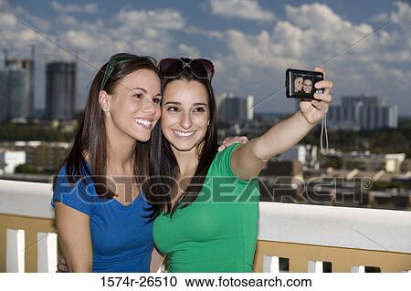 Stock Image - Teenage girl and a young woman photographing themselves. Fotosearch