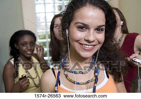 Teenage girl listening to music with her friends in the background View Large Photo Image Stock Image - Teenage girl listening to music with her friends in the background. Fotosearch
