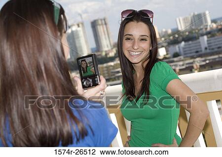 Stock Image - Teenage girl photographing a young woman. Fotosearch