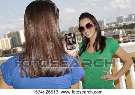 Teenage girl photographing a young woman View Large Photo Image Stock Image - Teenage girl photographing a young woman. Fotosearch