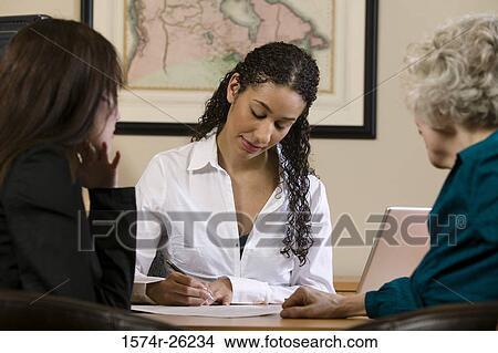 Three businesswomen sitting at a desk View Large Photo Image Picture - Three businesswomen sitting at a desk. Fotosearch