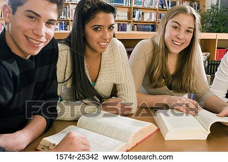 Three students sitting at a table in a library View Large Photo Image Stock Image - Three students sitting at a table in a library. Fotosearch