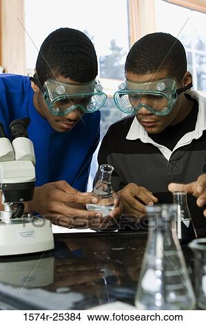 Picture - Two student looking at a beaker in a science lab. Fotosearch
