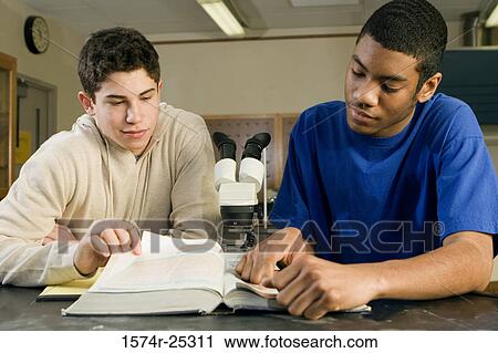 Stock Image - Two students reading a book in a science lab. Fotosearch