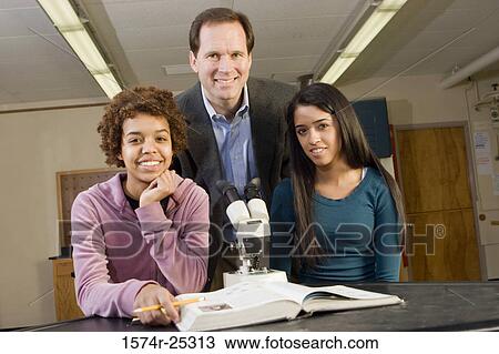 Stock Image - Two students with their teacher in a science lab. Fotosearch
