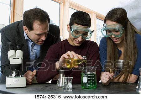Stock Photograph - Two students with their teacher performing an experiment in a science lab. Fotosearch