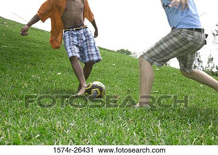 Stock Image - Two teenage boys kicking a soccer ball. Fotosearch