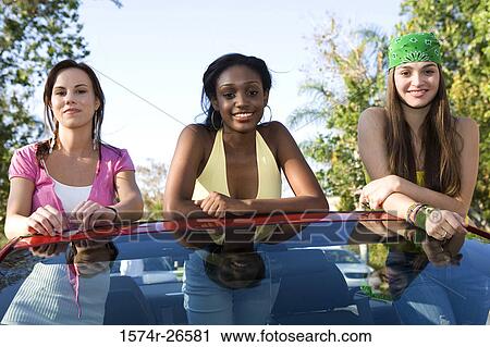 Two teenage girls and a young woman leaning on a car windshield View Large Photo Image Stock Image - Two teenage girls and a young woman leaning on a car windshield. Fotosearch