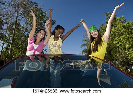 Two teenage girls and a young woman standing in a convertible car View Large Photo Image Stock Image - Two teenage girls and a young woman standing in a convertible car. Fotosearch