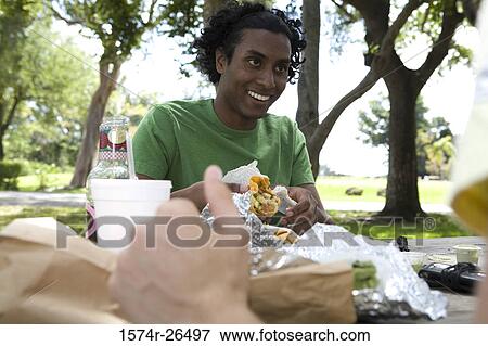 Stock Photo - Young man holding a sandwich and smiling. Fotosearch