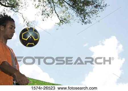 Young man looking at a soccer ball in mid-air View Large Photo Image Stock Image - Young man looking at a soccer ball in mid-air. Fotosearch