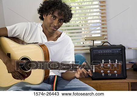 Stock Image - Young man playing a guitar. Fotosearch