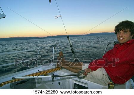 Young man sitting on a sailboat View Large Photo Image Stock Image - Young man sitting on a sailboat. Fotosearch