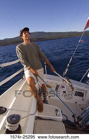 Young man standing on a sailboat and pulling a rope View Large Photo Image Stock Photography - Young man standing on a sailboat and pulling a rope. Fotosearch