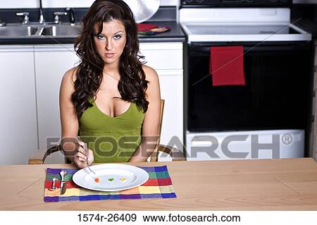 Stock Photo - Young woman sitting at a dining table. Fotosearch