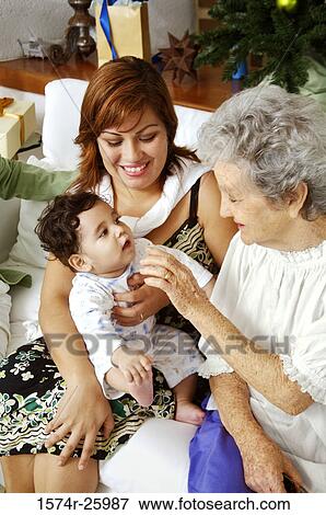Young woman with her baby and a senior woman sitting on a couch View Large Photo Image Stock Photo - Young woman with her baby and a senior woman sitting on a couch. Fotosearch