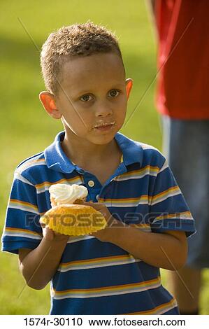 Boy holding a cupcake at park View Large Photo Image Stock Image - Boy holding a cupcake at park. Fotosearch