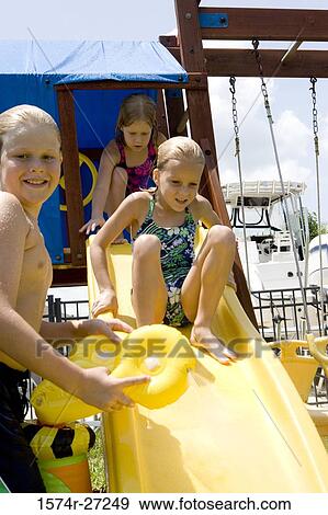Boy holding a toy while girls playing on slide View Large Photo Image Stock Photo - Boy holding a toy while girls playing on slide. Fotosearch