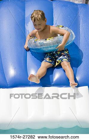 Boy on water slide wearing inflatable ring View Large Photo Image Stock Image - Boy on water slide wearing inflatable ring. Fotosearch