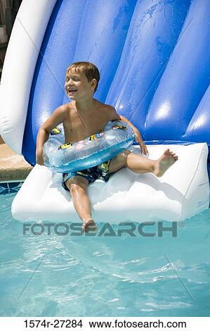 Boy on waterslide wearing inflatable ring View Large Photo Image Picture - Boy on waterslide wearing inflatable ring. Fotosearch