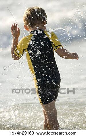 Boy playing in water at the beach View Large Photo Image Stock Image - Boy playing in water at the beach. Fotosearch