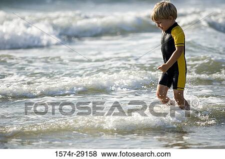 Boy playing in water at the beach View Large Photo Image Stock Photo - Boy playing in water at the beach. Fotosearch