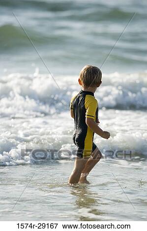 Stock Photo - Boy playing in water at the beach. Fotosearch