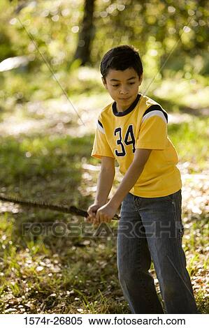 Boy playing with a stick on grass at forest View Large Photo Image Stock Photography - Boy playing with a stick on grass at forest. Fotosearch