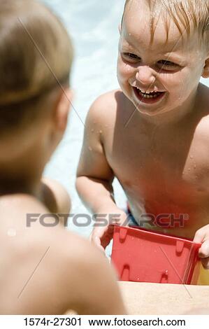 Stock Image - Boy playing with his friend at swimming pool. Fotosearch